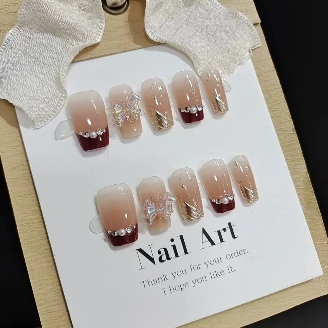 Krátké nalepovací nehty s francouzskou špičkou, zlatý glitr a design mašle
